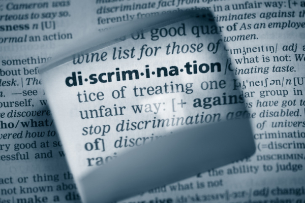 A dictionary with the word "discrimination" magnified and part of the definition shown in black and white